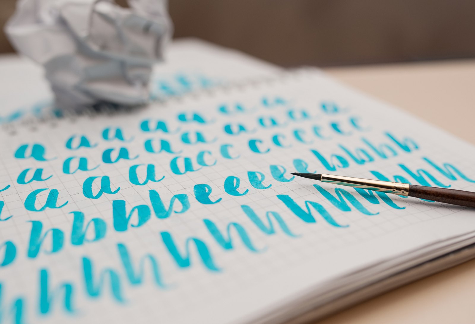 Teal watercolor brush lettering practice strokes in a sketchbook